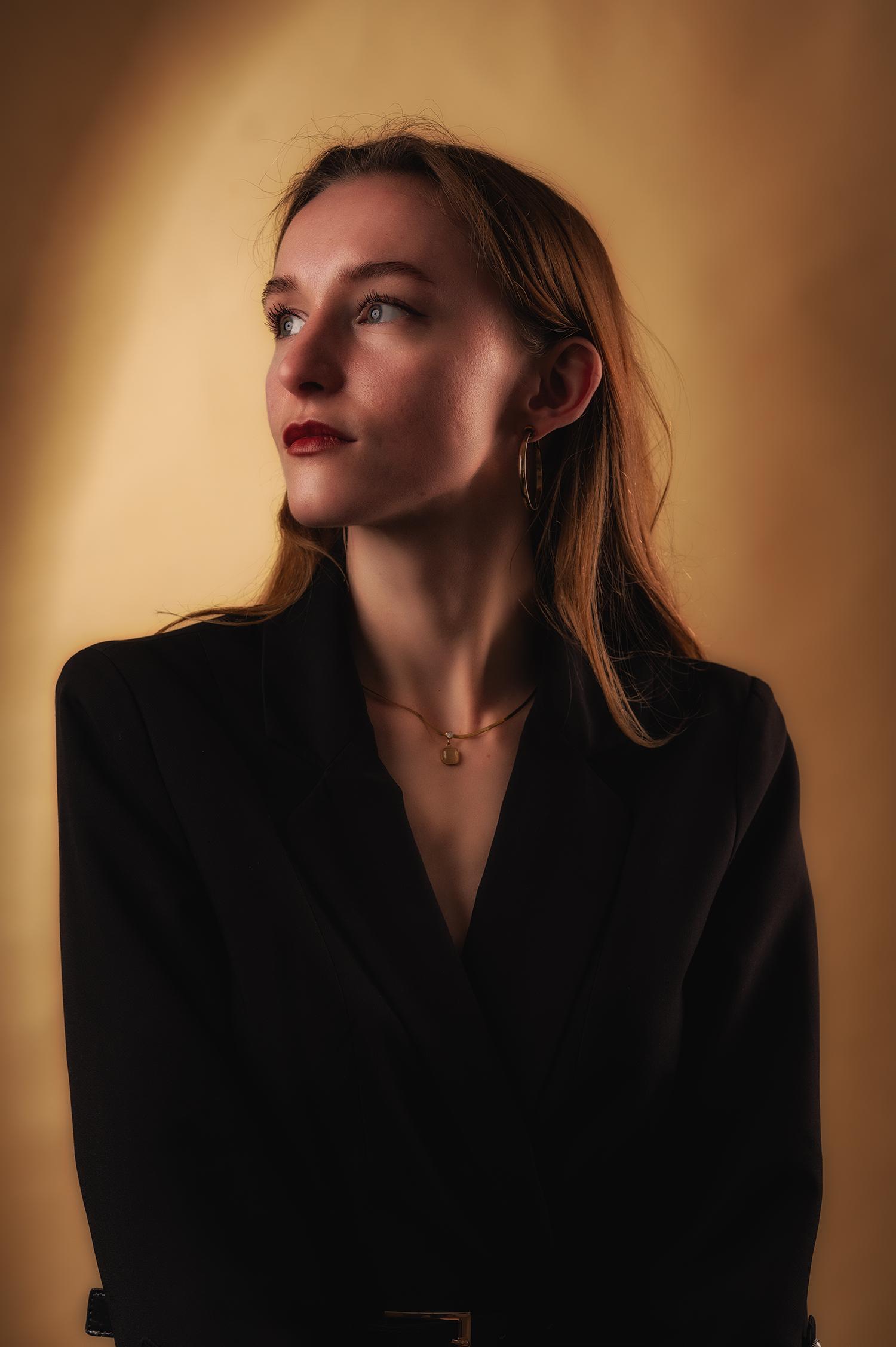 Alicja Sochacka im schwarzen Blazer vor warmem Studiohintergrund